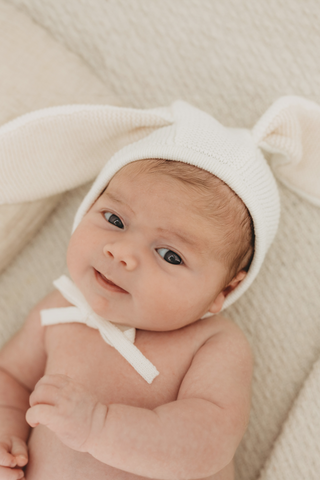 Baby wearing a bunny ear bonnet in white